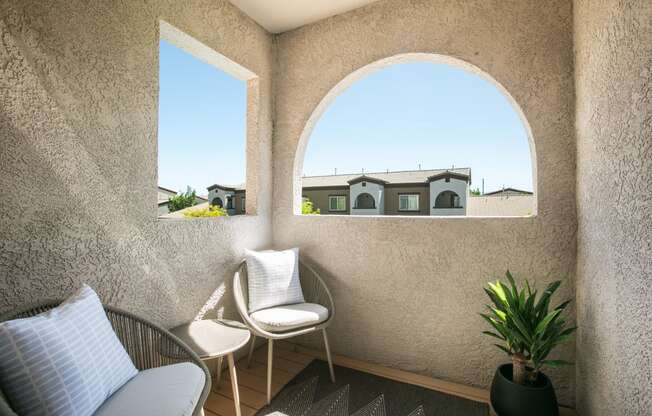 a small patio with two chairs and a potted plant