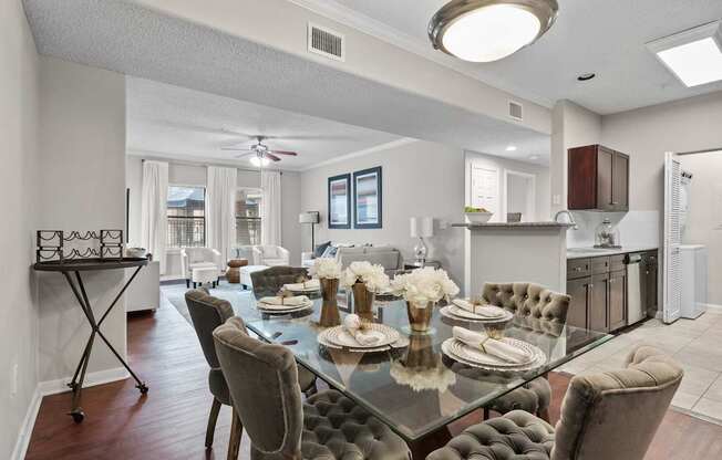 A modern dining room with a glass table and grey chairs.
