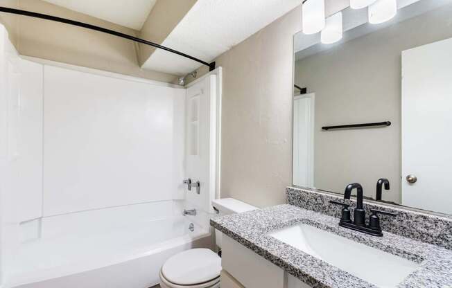 A bathroom with a toilet, sink, and mirror.