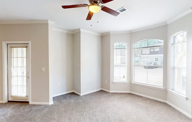 A room with a ceiling fan and carpeted floor.