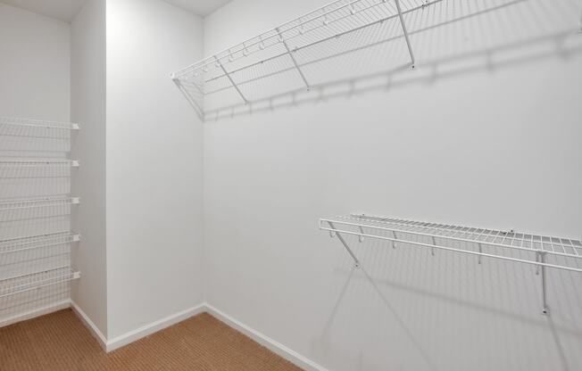 room with white walls and shelves and a closet with hanging racks