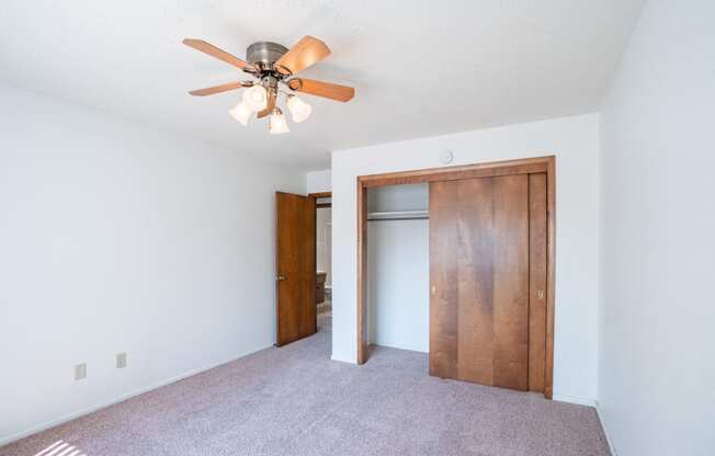 a bedroom with a ceiling fan and a closet. Fargo, ND Betty Ann Apartments