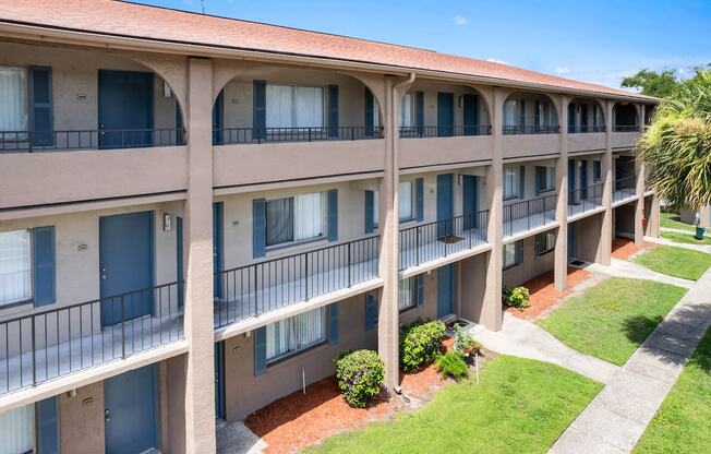 an exterior view of a building with balconies and a lawn