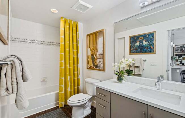 A bathroom with a toilet, sink, and a painting on the wall.