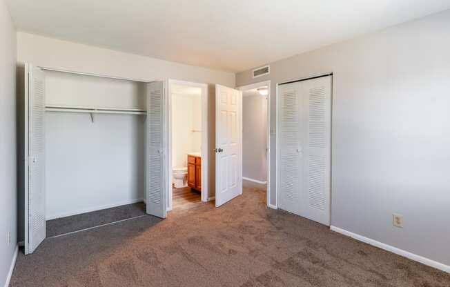 a spacious bedroom with closet doors and a bathroom