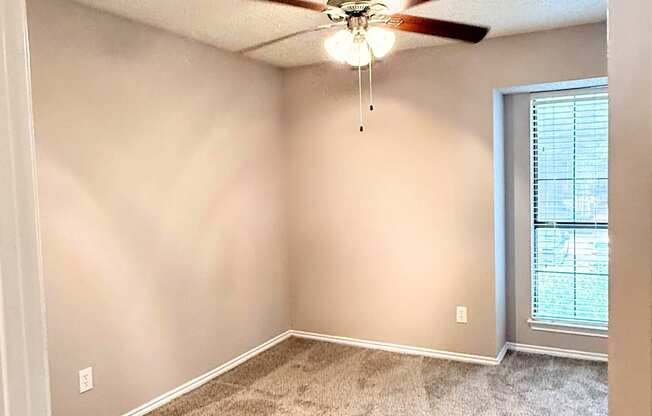 A room with a ceiling fan and carpeted floor.