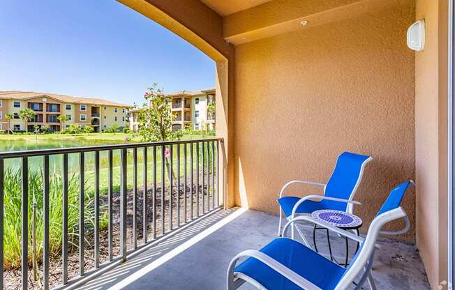 A balcony with blue chairs and a table.