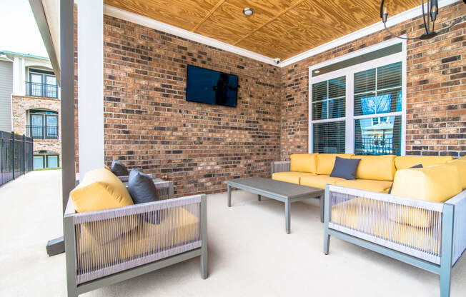 a patio with couches and tables and a brick wall