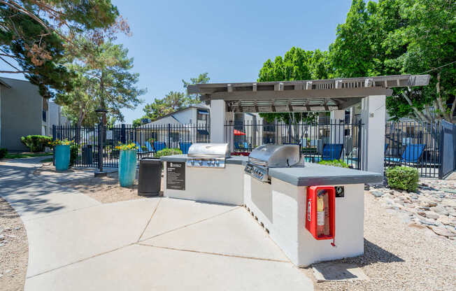 A white kiosk with a red fire extinguisher is in the foreground of a sunny day.