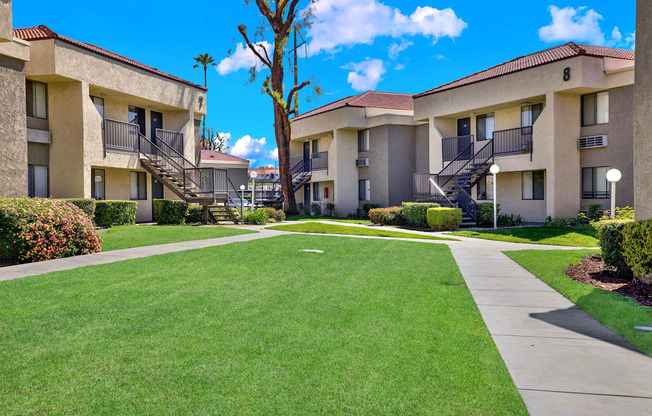 A sunny day at a well-kept apartment complex with green lawns and clear skies.