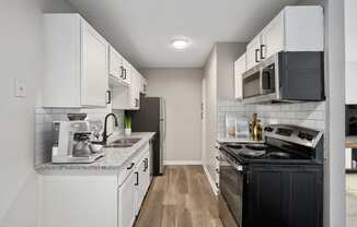 a kitchen with white cabinets and black appliances