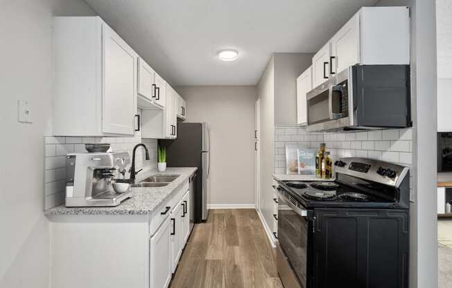 a kitchen with white cabinets and black appliances