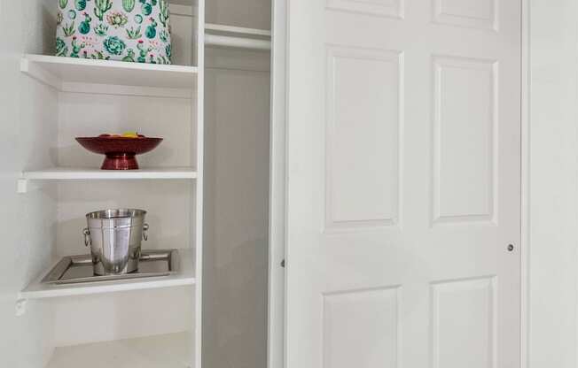 A white pantry with an open door and a bowl on the shelf at Urban WalkApartments on 6th Avenue, Phoenix, AZ