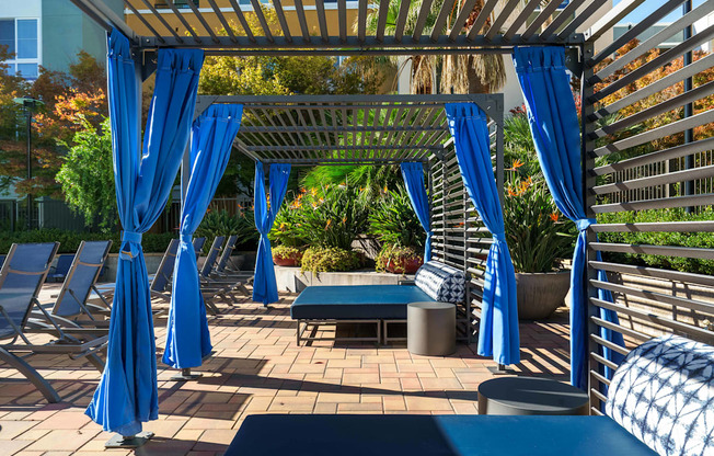 A patio with blue umbrellas and a bench.