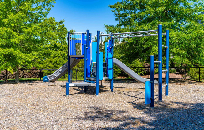 a playground with blue playset and slides in a park