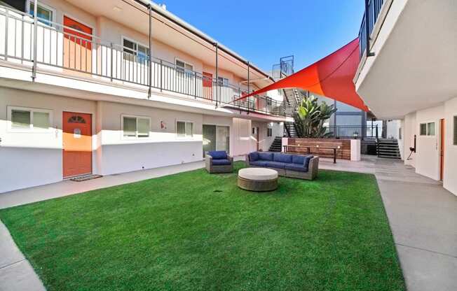 the courtyard of a building with green grass and furniture