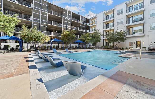 an apartment pool with lounge chairs in front of an apartment building