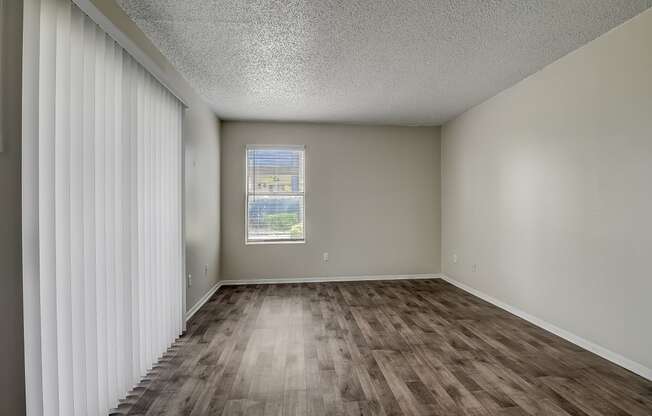 an empty living room with a window and curtains