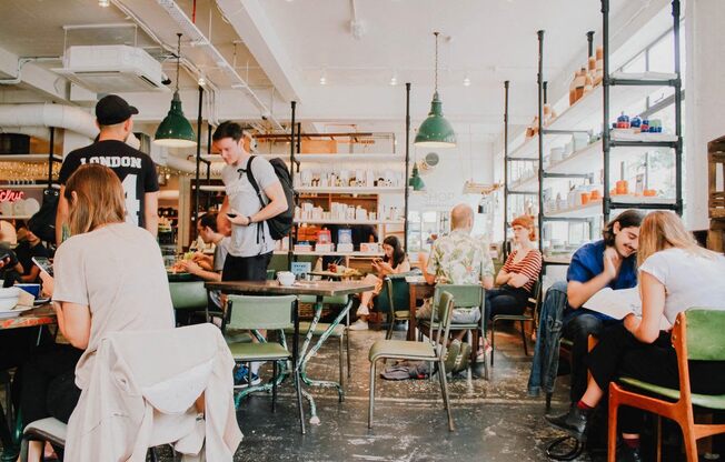 A group of people are sitting and standing in a restaurant.