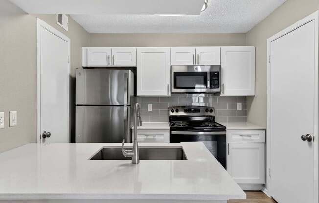 A kitchen with white cabinets and appliances.