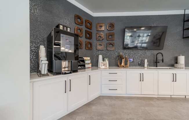 a kitchen with white cabinets and a tv on the wall