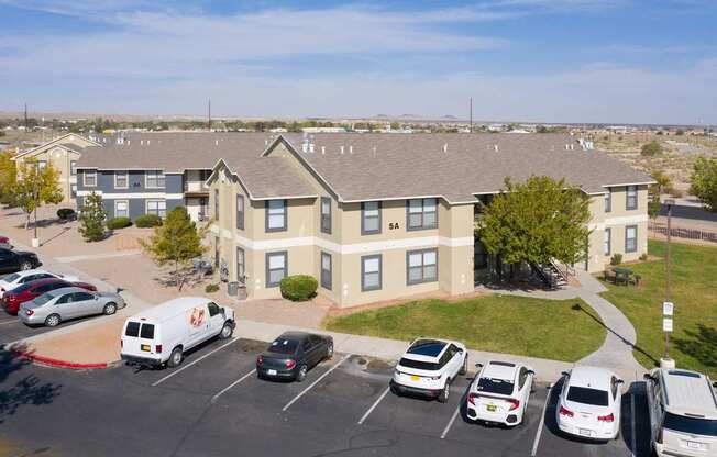 A parking lot with cars and a white van in front of a building.