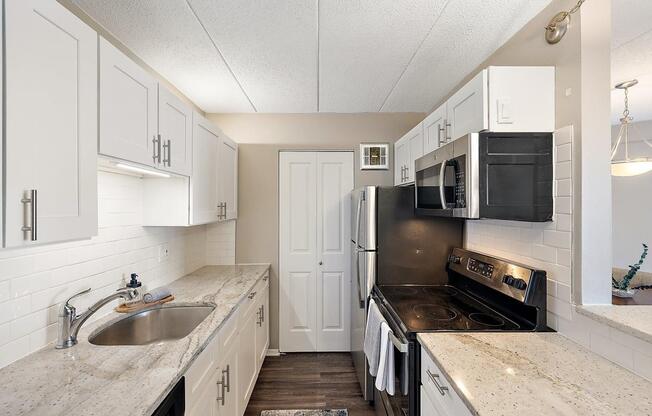 a kitchen with black appliances and white cabinets at Troy Place Apartments - Troy, MI, Troy, Michigan