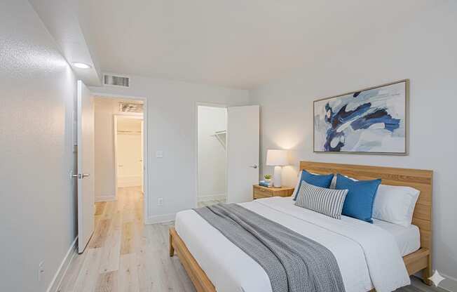 A bedroom with a bed, nightstand, and a painting on the wall.