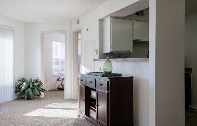 A view of the living room in the model unit at Skyler Ridge Apartments, with a dresser and a mirror on the wall.