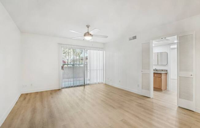 A room with a sliding glass door and a ceiling fan.