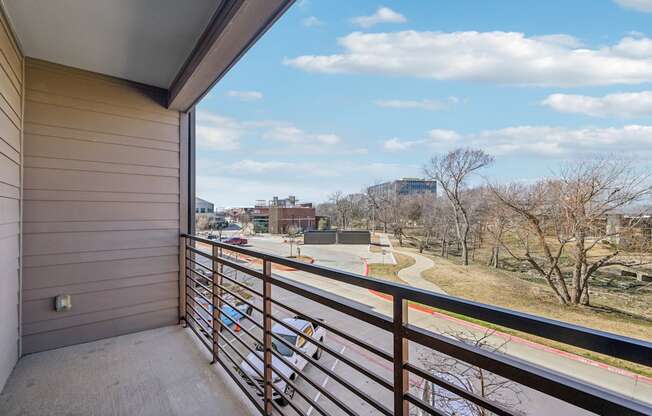 A balcony with a view of a road and trees.