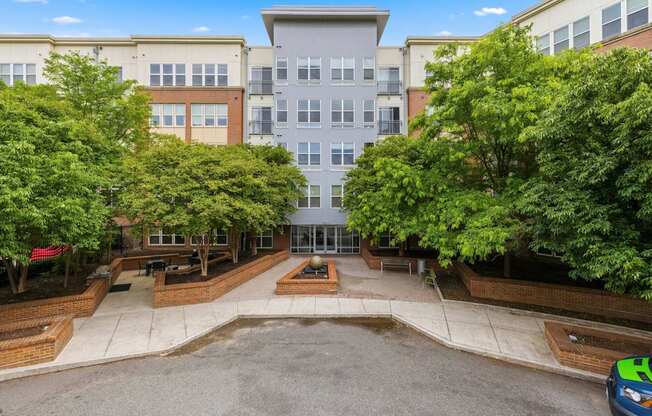 A car is parked on the right side of a courtyard with a building in the background.
