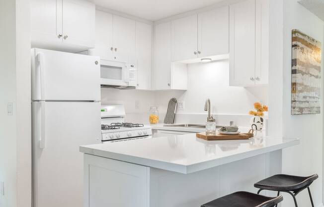 a white kitchen with a white counter top and a white refrigerator