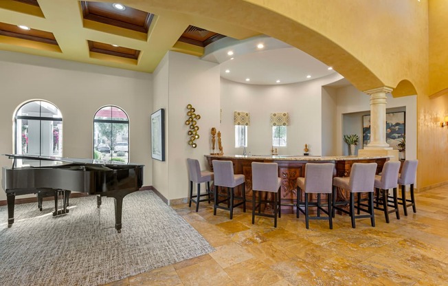 A grand piano is situated in a room with a bar and chairs.