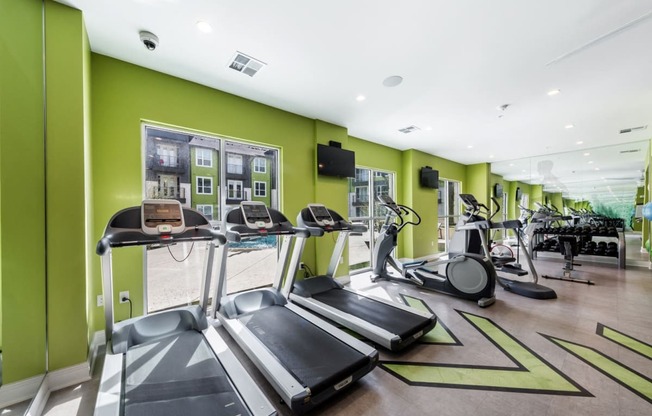 Cardio machines in front of large windows with cable TV