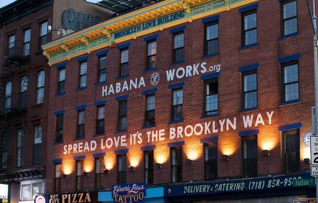 a building with a sign that reads spread love its the way at The Paxton, Brooklyn, NY