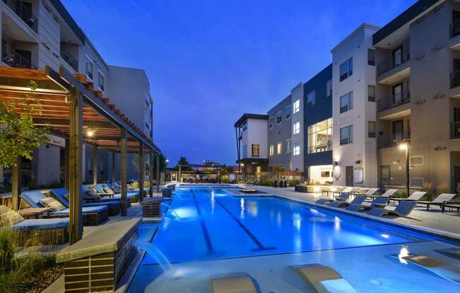 a swimming pool in the middle of apartments at night