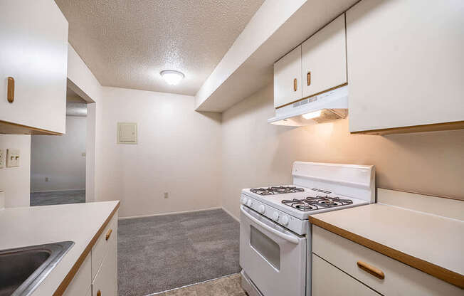 A kitchen with a white stove top oven leading to a dining room at Seville Apartments, Michigan