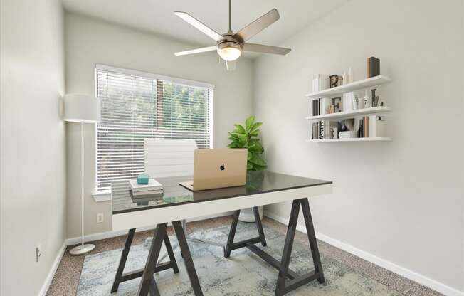 a home office with a ceiling fan and a laptop on a desk