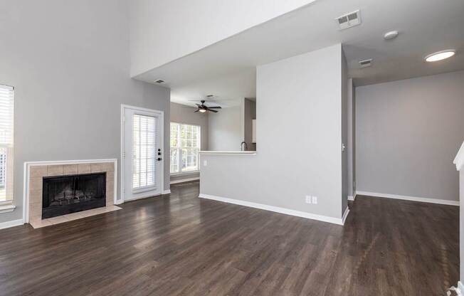 A spacious living room with wood flooring and a fireplace.