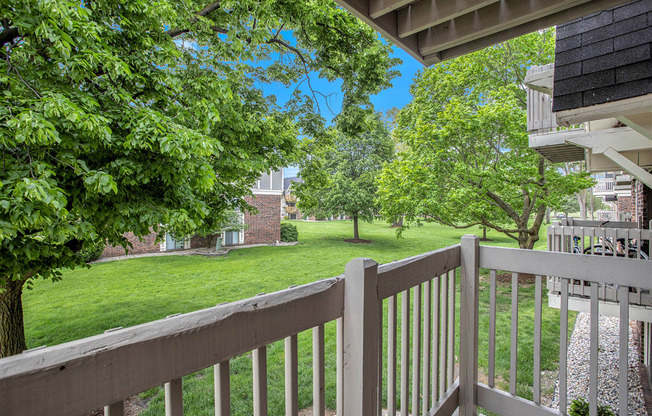 the view from a private balcony with mature shade trees at Fairlane Apartments in Springfield, MI