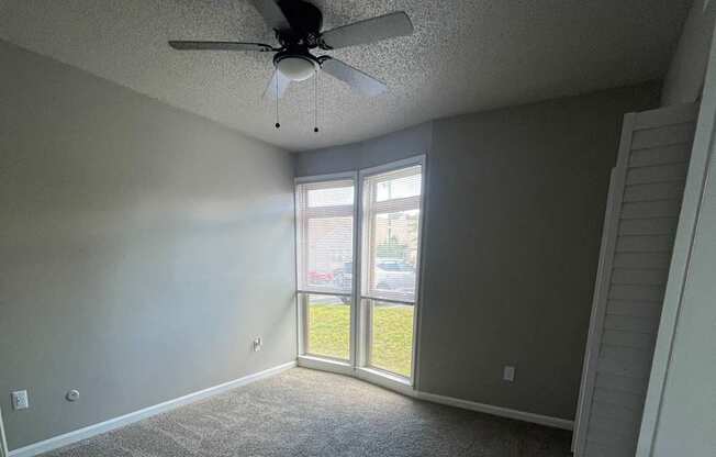 A room with a ceiling fan and a window.