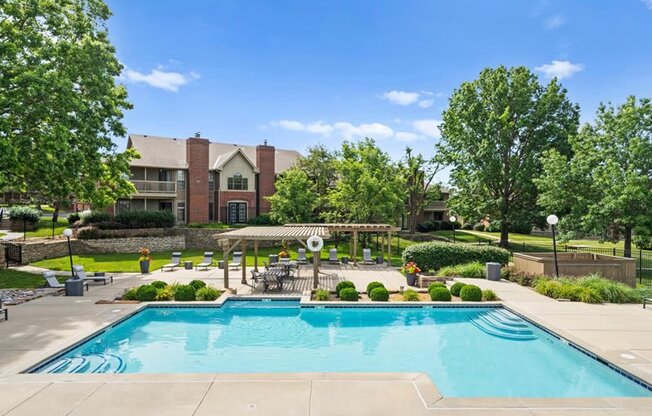 a swimming pool with trees and a building in the background at Highland Park Apartment Homes, Overland Park, KS, 66214