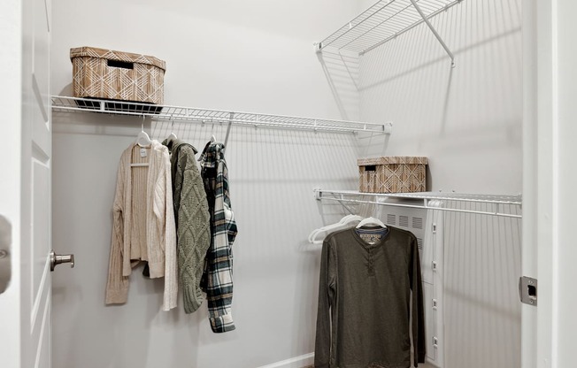 A white closet with clothes hanging on a wire rack.