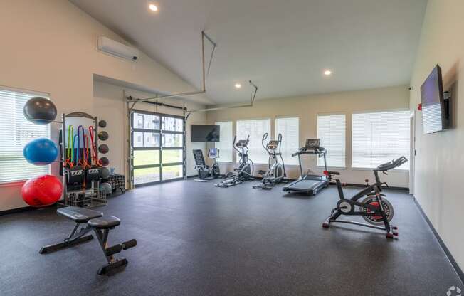 a gym with treadmills and other exercise equipment and windows