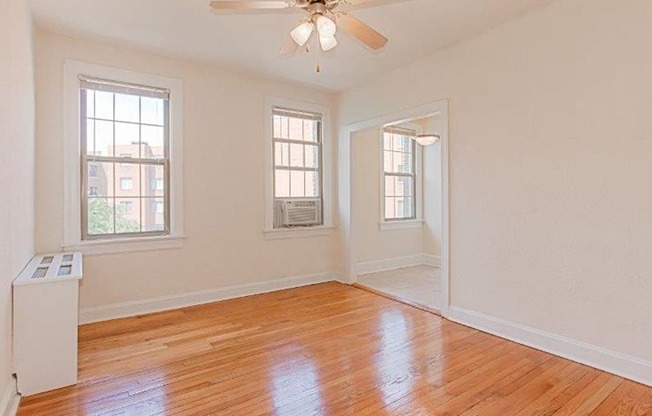 vacant living area with hardwood flooring, ceiling fan, and large windows at parkside apartments in washington dc