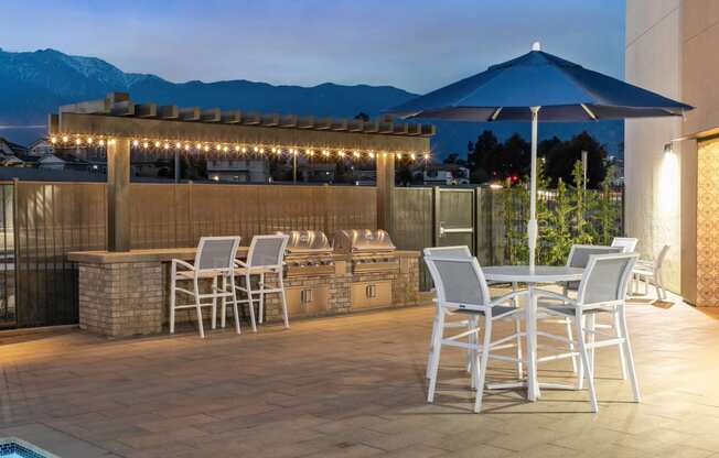 a patio with a bar and tables with chairs and umbrellasat Westbury Apartments, Rancho Cucamonga