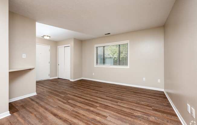 an empty living room with wood flooring and a window