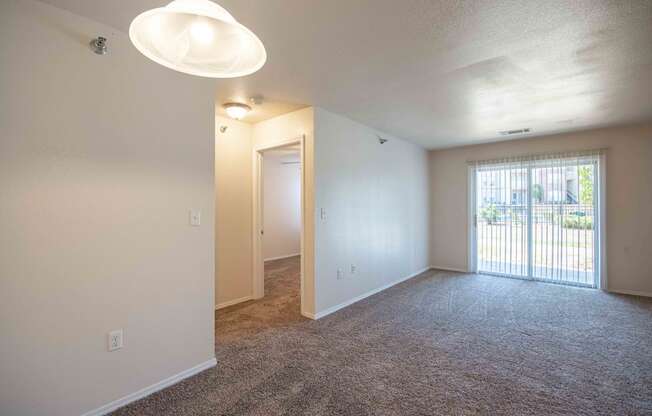 Living room with walkway to bedroom and glass doors with blinds