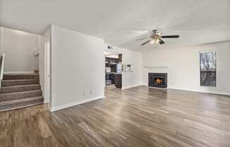 an empty living room with a ceiling fan and a fireplace